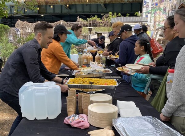 several people help serve a meal during an outdoor promotional event