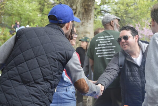 Two individuals shaking hands at an outdoor event