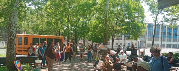 several people gather in front of an electric school bus at an outdoor sustainability event